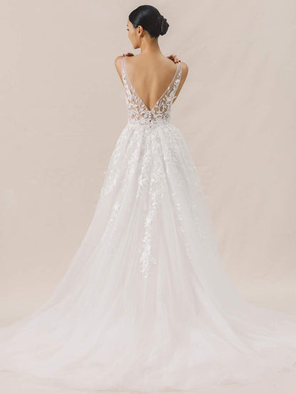 Woman wearing a white wedding dress with intricate detailing on a beige background