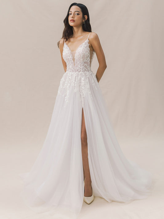 Woman wearing a white wedding dress with floral details on a beige background