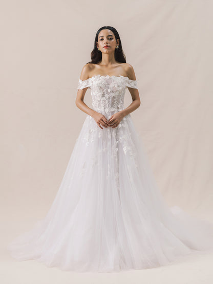 Woman wearing a white off-shoulder wedding dress with floral details on a beige background