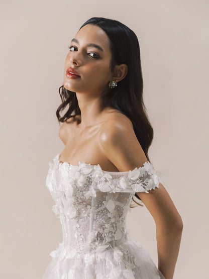 Woman wearing a white off-shoulder lace dress against a beige background