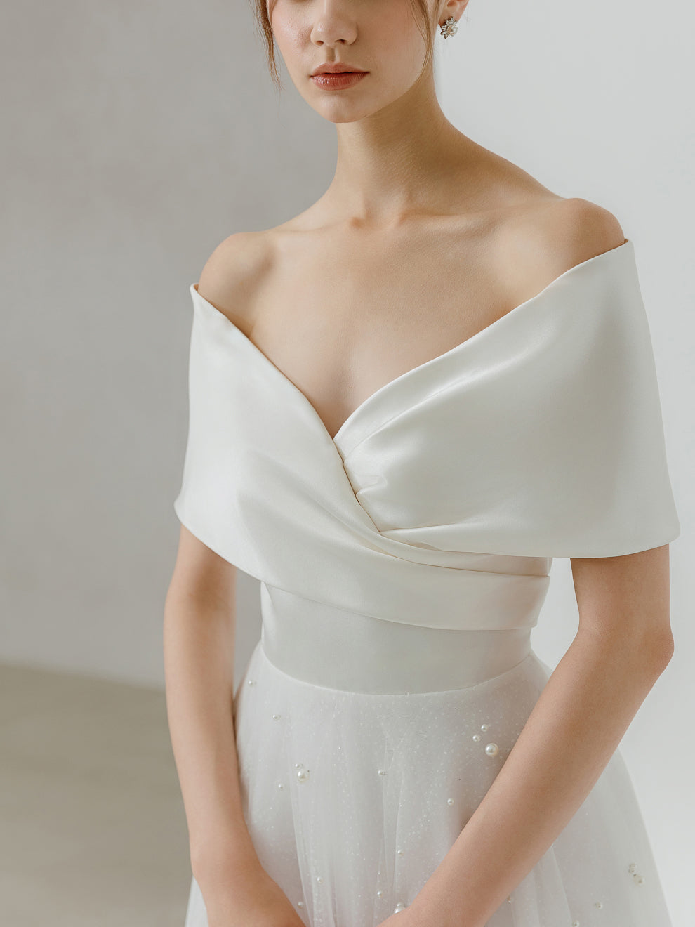 White off-shoulder dress worn by a model against a neutral background