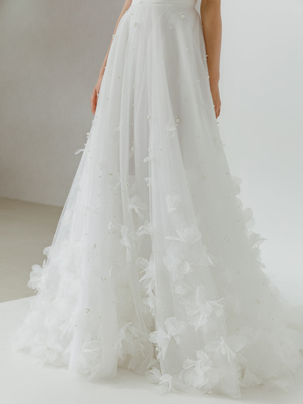 White wedding dress with floral details on a plain background