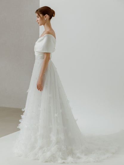 Woman wearing a white wedding dress with a soft, flowing skirt against a plain background