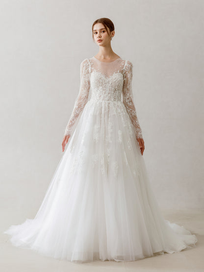 Model wearing a white lace wedding dress with long sleeves against a plain background