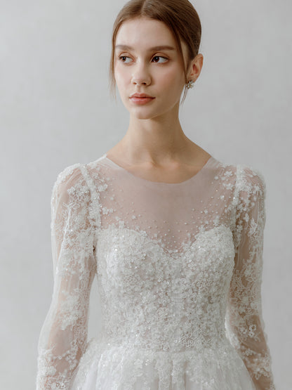 Woman wearing a white lace wedding dress against a plain background
