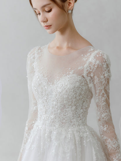 Woman wearing a lace wedding dress with long sleeves on a plain background