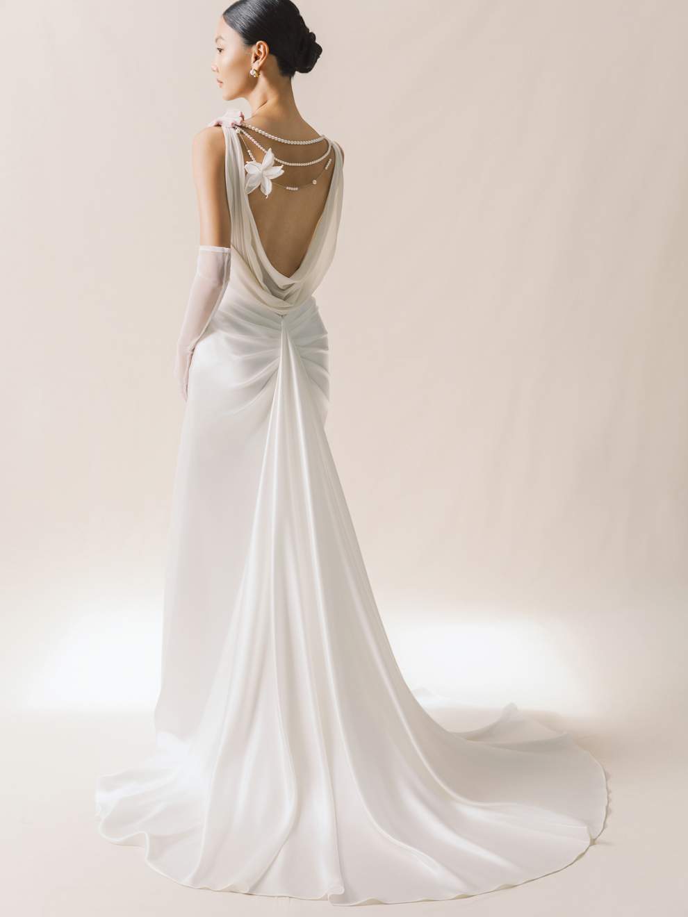 White wedding dress with a long train and intricate back design on a plain background