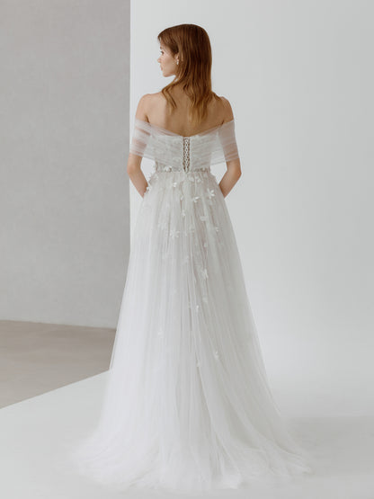 Woman wearing a white wedding dress with a subtle back design on a plain background