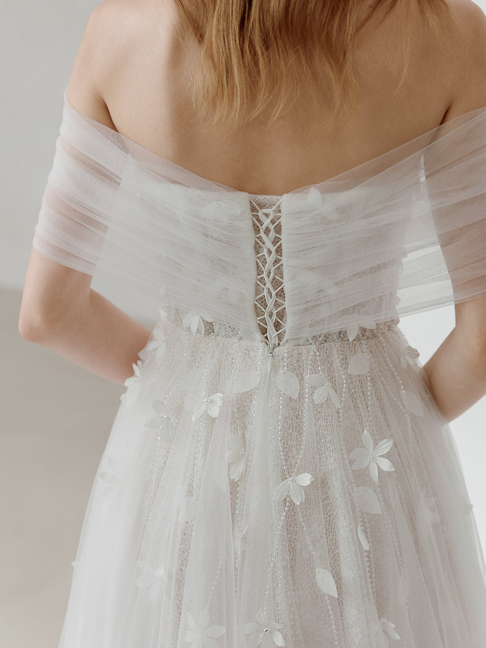 White lace dress with floral details on a neutral background