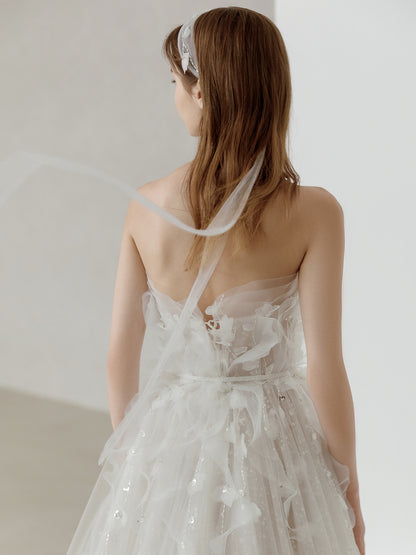 Woman wearing a white floral dress with a sheer overlay against a plain background