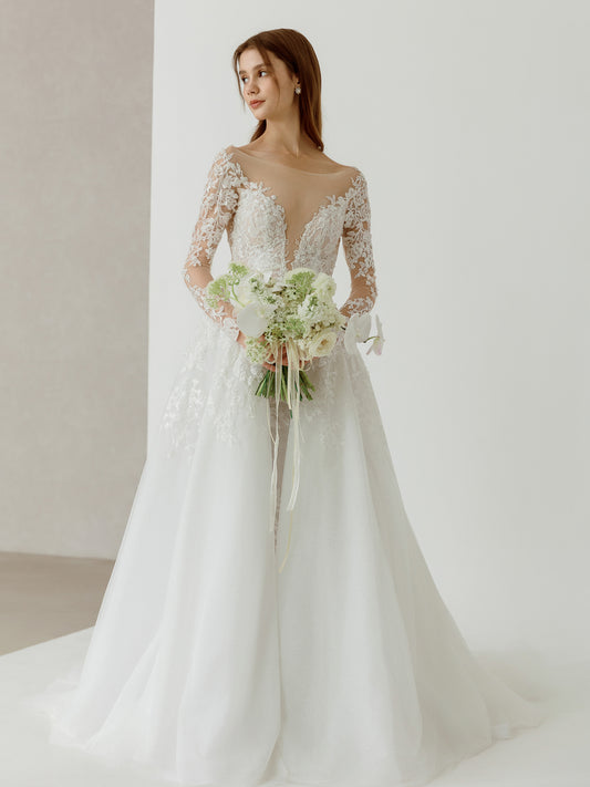 Woman in a white wedding dress holding a bouquet against a plain background