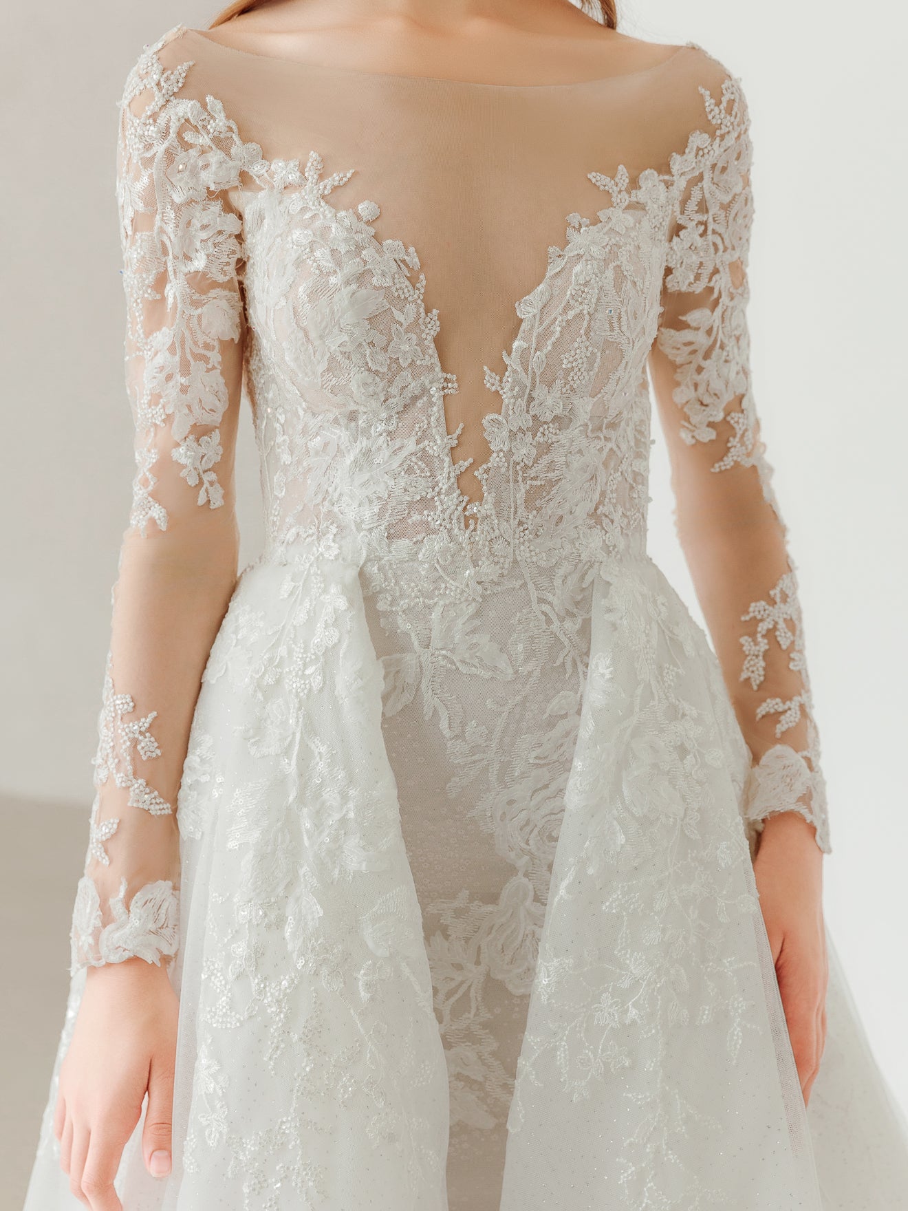 Lace wedding dress with long sleeves on a neutral background