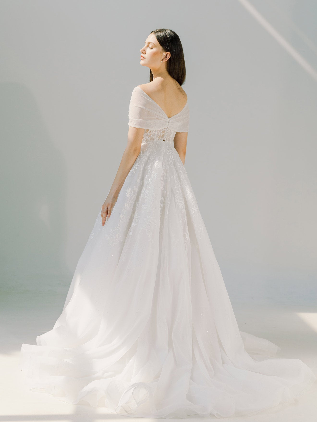 Woman wearing a white wedding dress against a light gray background