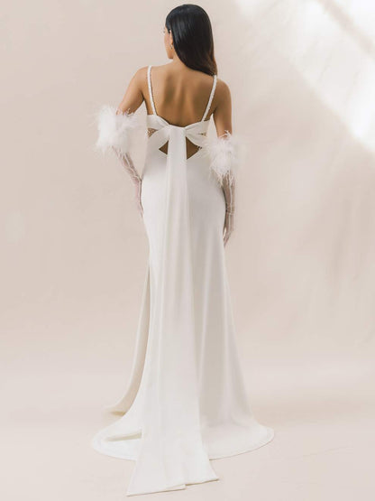 White wedding dress with feathered sleeves on a plain background