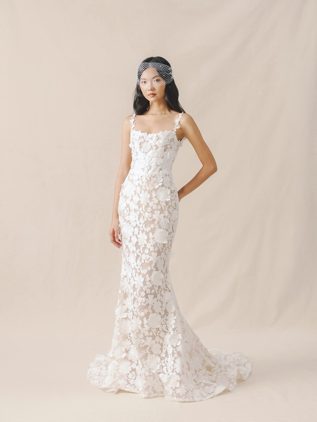 Woman wearing a white lace wedding dress against a beige background