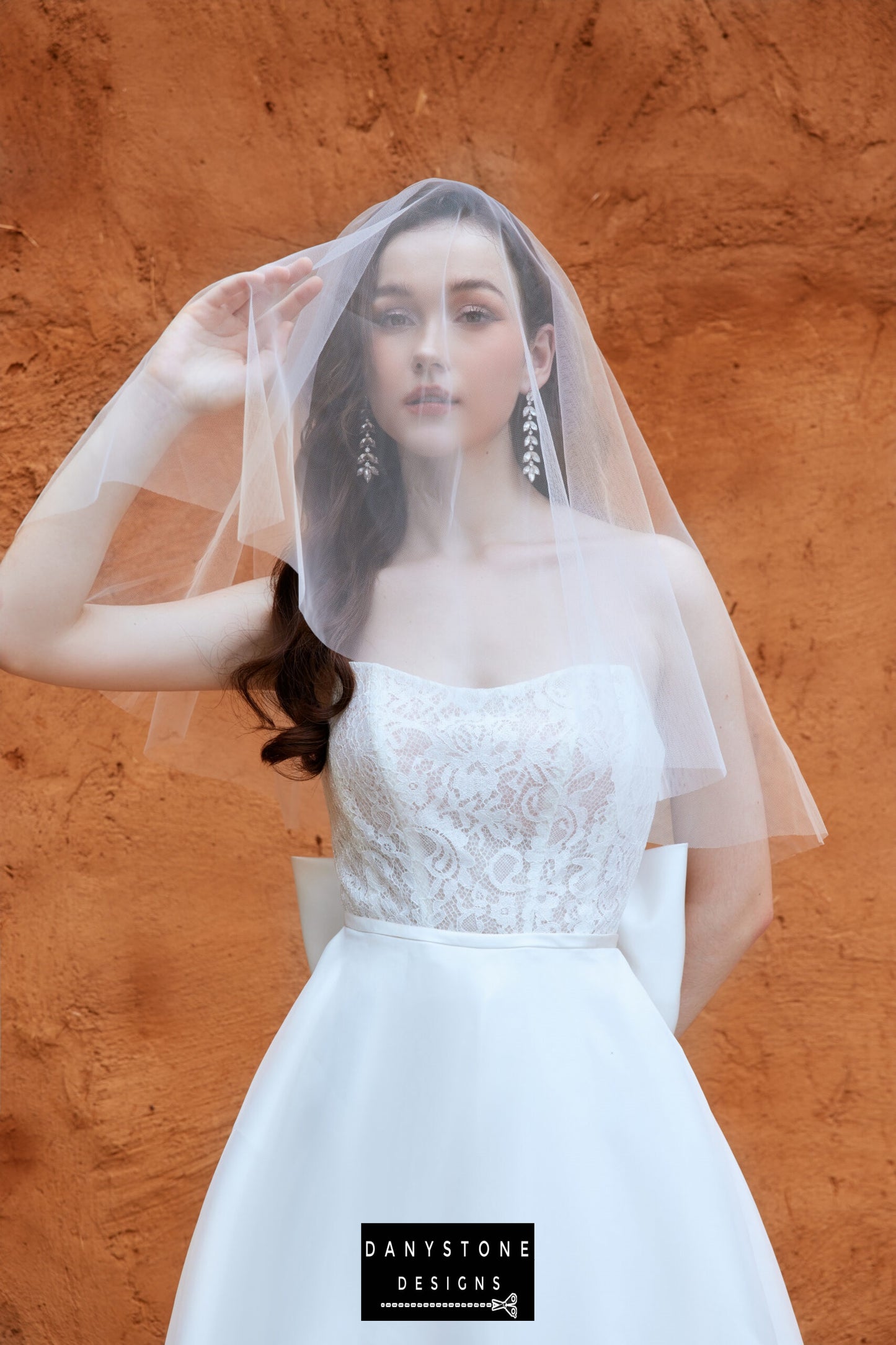 Close-up of the model wearing the full-length wedding dress with a lace bodice and sheer veil, by Danystone Designs.