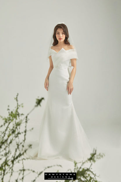 Back view of elegant off-shoulder wedding dress with large bow and flowing train – Danystone Designs