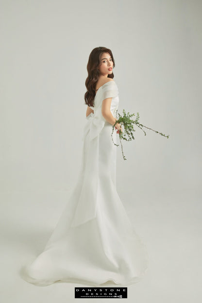 Stylish bride in off-shoulder wedding dress with wrap detail, holding a branch – Danystone Designs