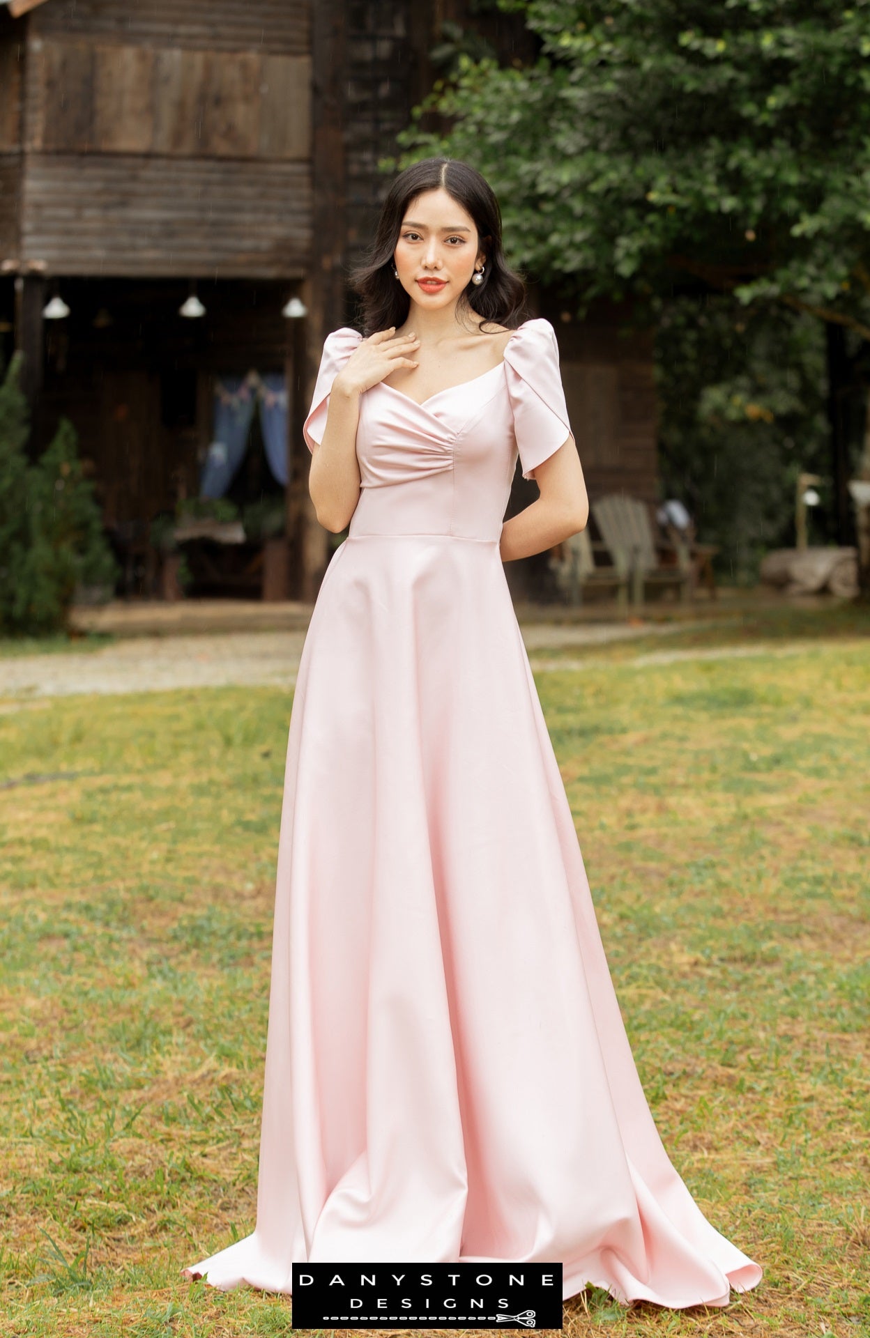 Pink short-sleeved dress with pleated front panels modeled outdoors