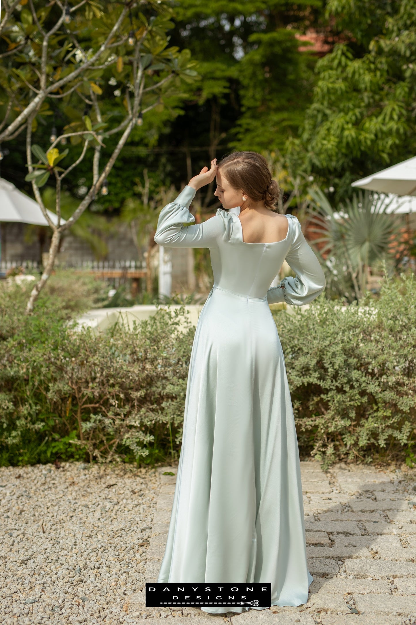 Lady in an olive silk dress with long sleeves and a square neck