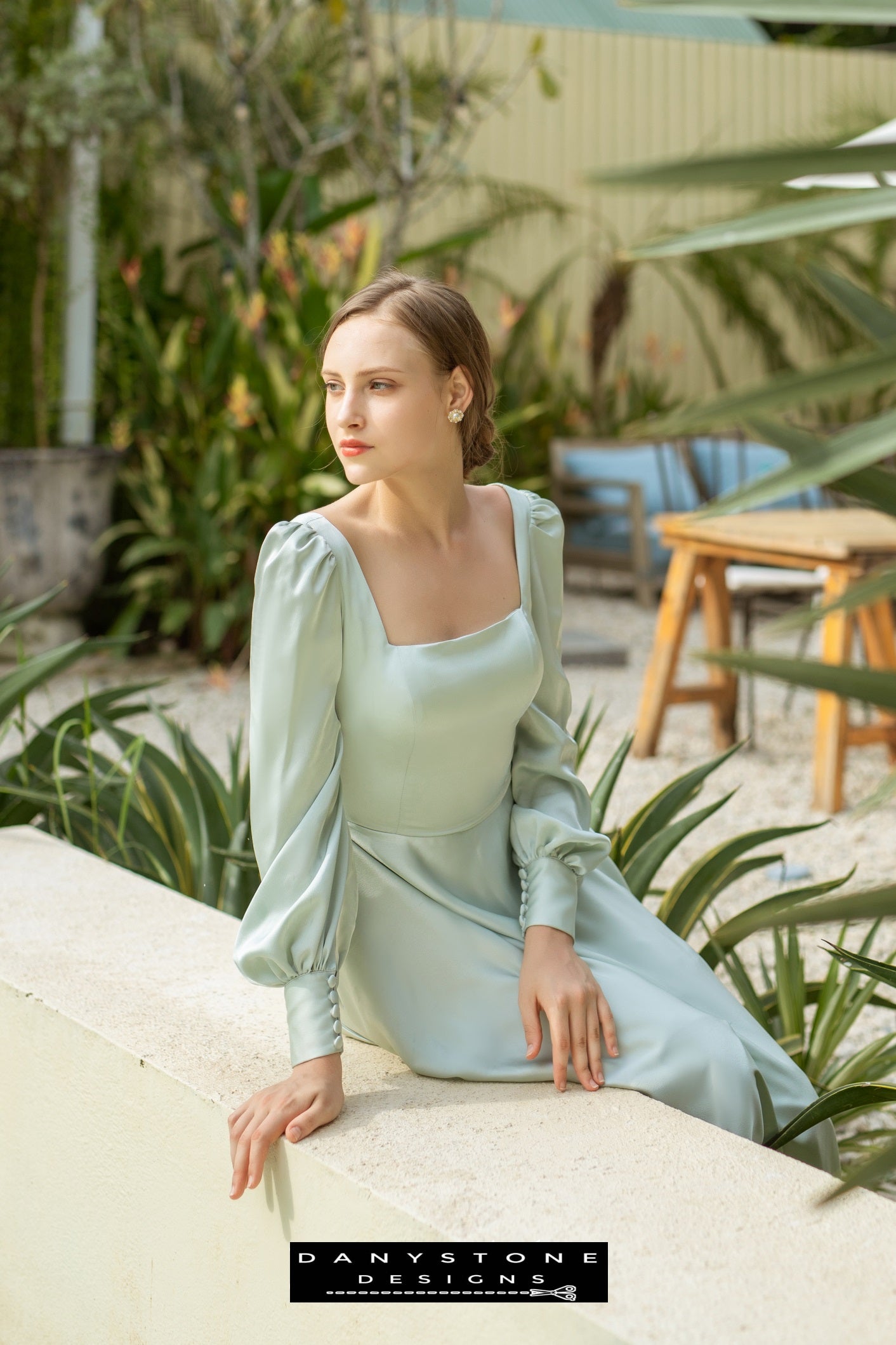 Elegant woman in an olive long-sleeved silk dress standing outside