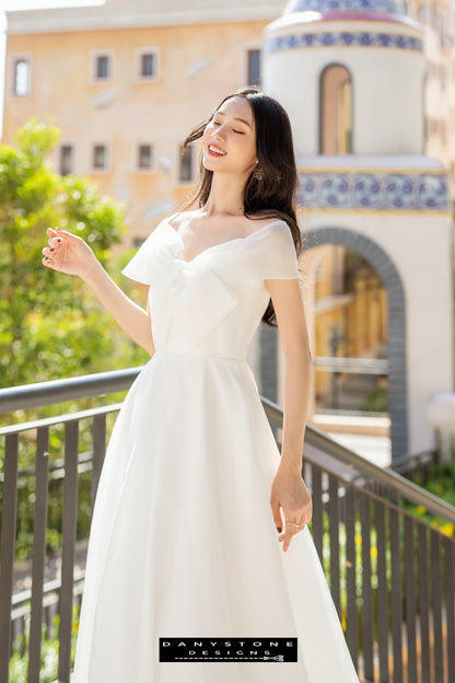 Image 5: Bride in a silk chiffon wedding dress with bow accents, enjoying the sunlight on a balcony.