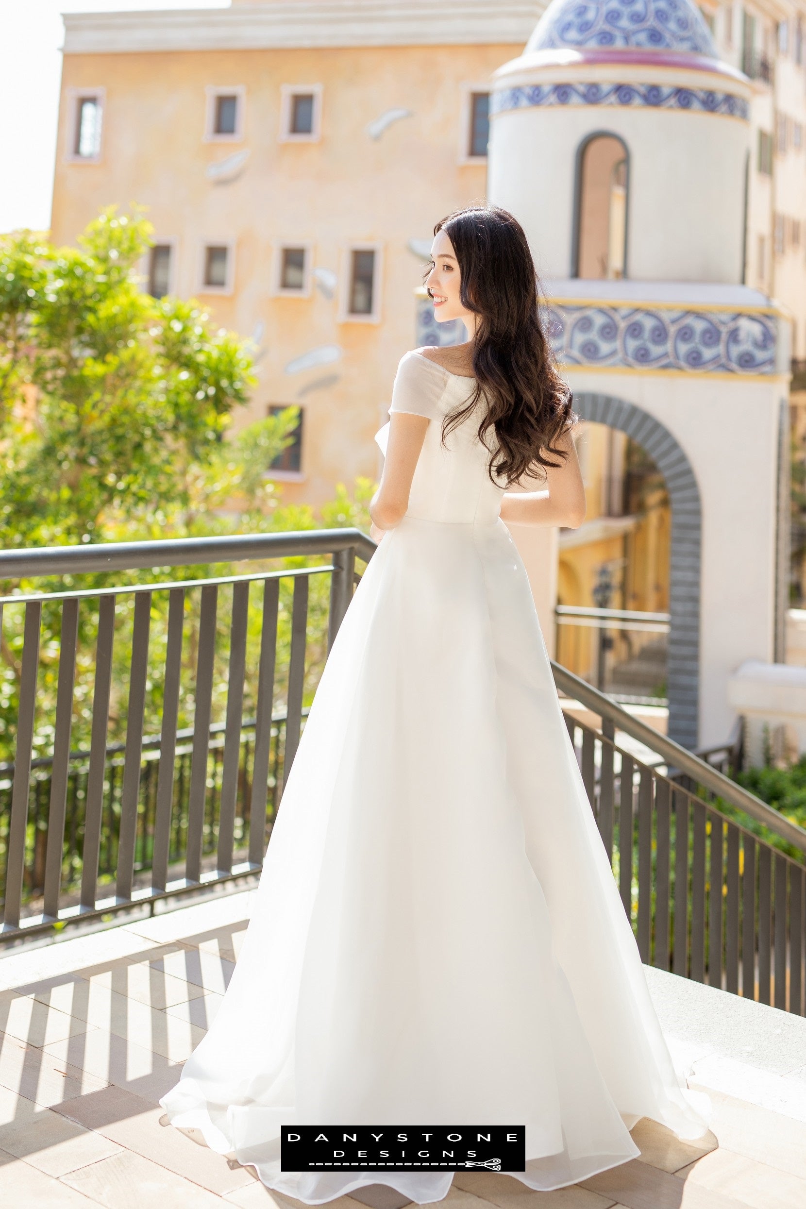 Image 3: Back view of a bride in a silk chiffon wedding dress with bow accents, showing the flowing silhouette.