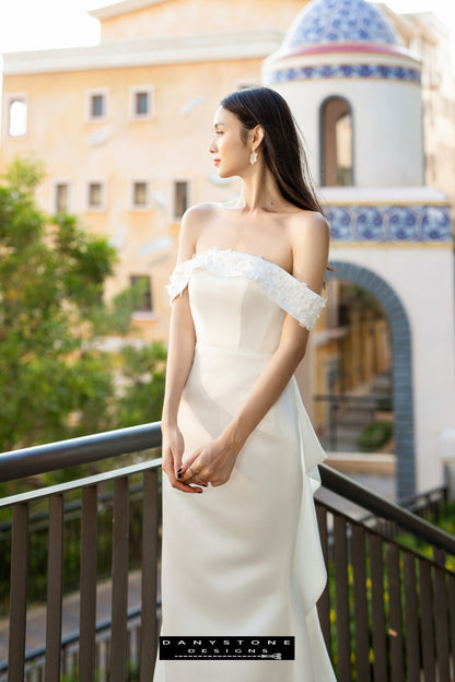 Side view of a bride in a flat shoulder fishtail wedding dress with 3D floral accents, showcasing the silhouette.