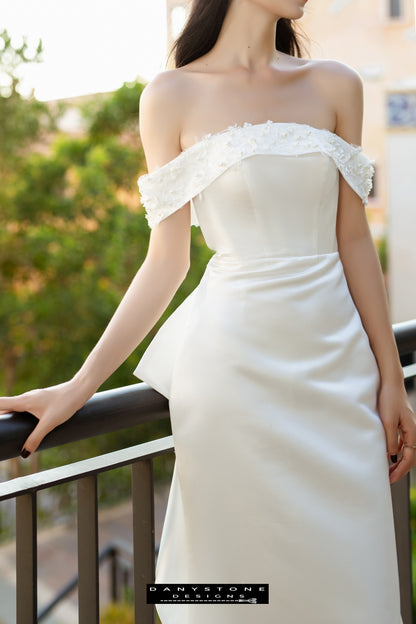 Close-up of a bride in a flat shoulder fishtail wedding dress with 3D floral accents, highlighting the embossed flowers.