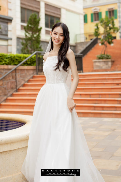 Image 2: Side view of a bride in a camisole wedding dress with mesh beads, smiling against a colorful urban backdrop.