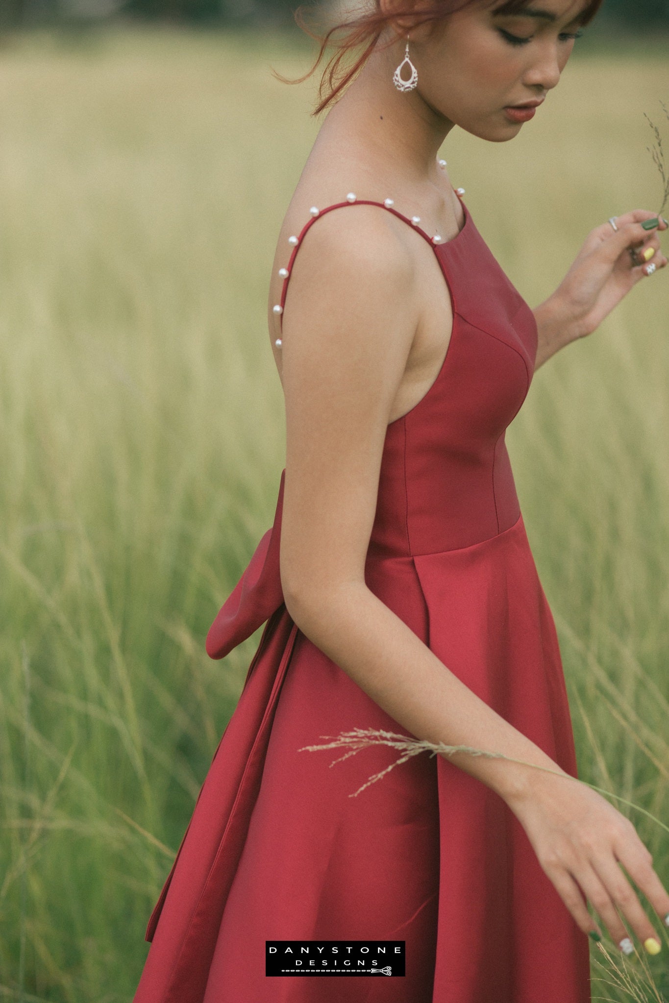 Close-up of the oversized bow on the back of a red evening dress with pearl straps