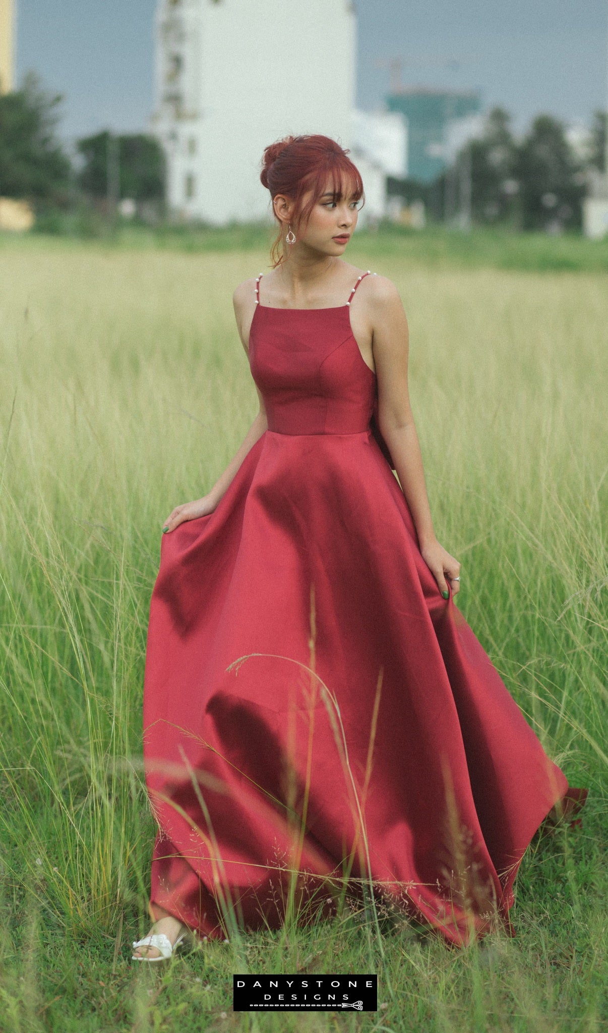 Woman in a red Tafta dress with a large bow posing in a lush green field