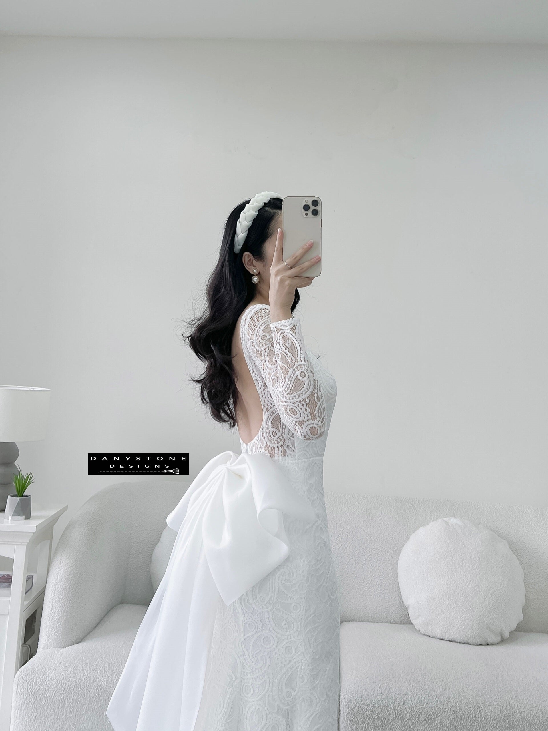 Bride in lace fishtail dress with full U back and silk chiffon bow, front view.