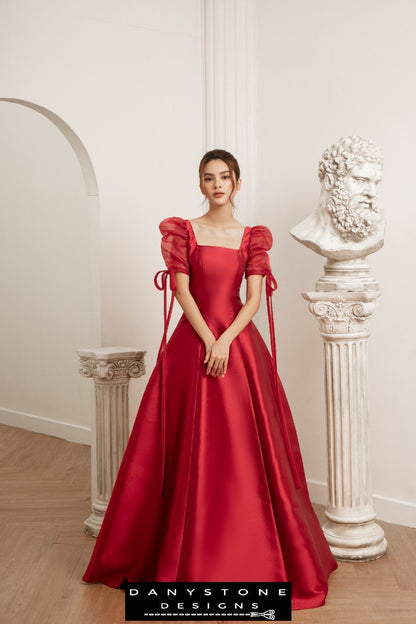 Woman wearing a seven-piece red wedding dress with silk chiffon sleeves standing in a classical setting