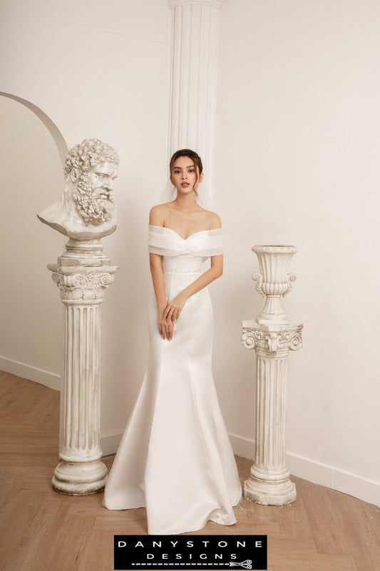 Bride in fishtail wedding dress with flat shoulders and silk chiffon trim, full front view.