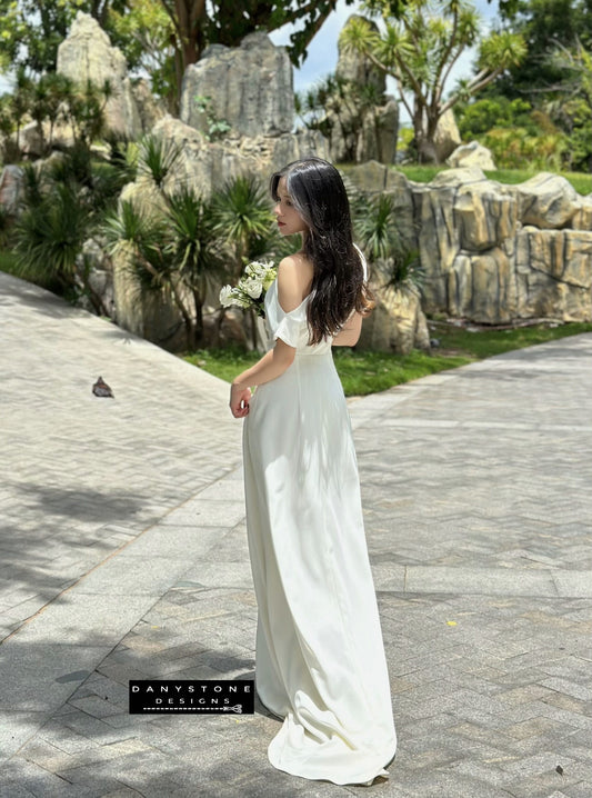 Model wearing an off-the-shoulder satin wedding dress, back view.