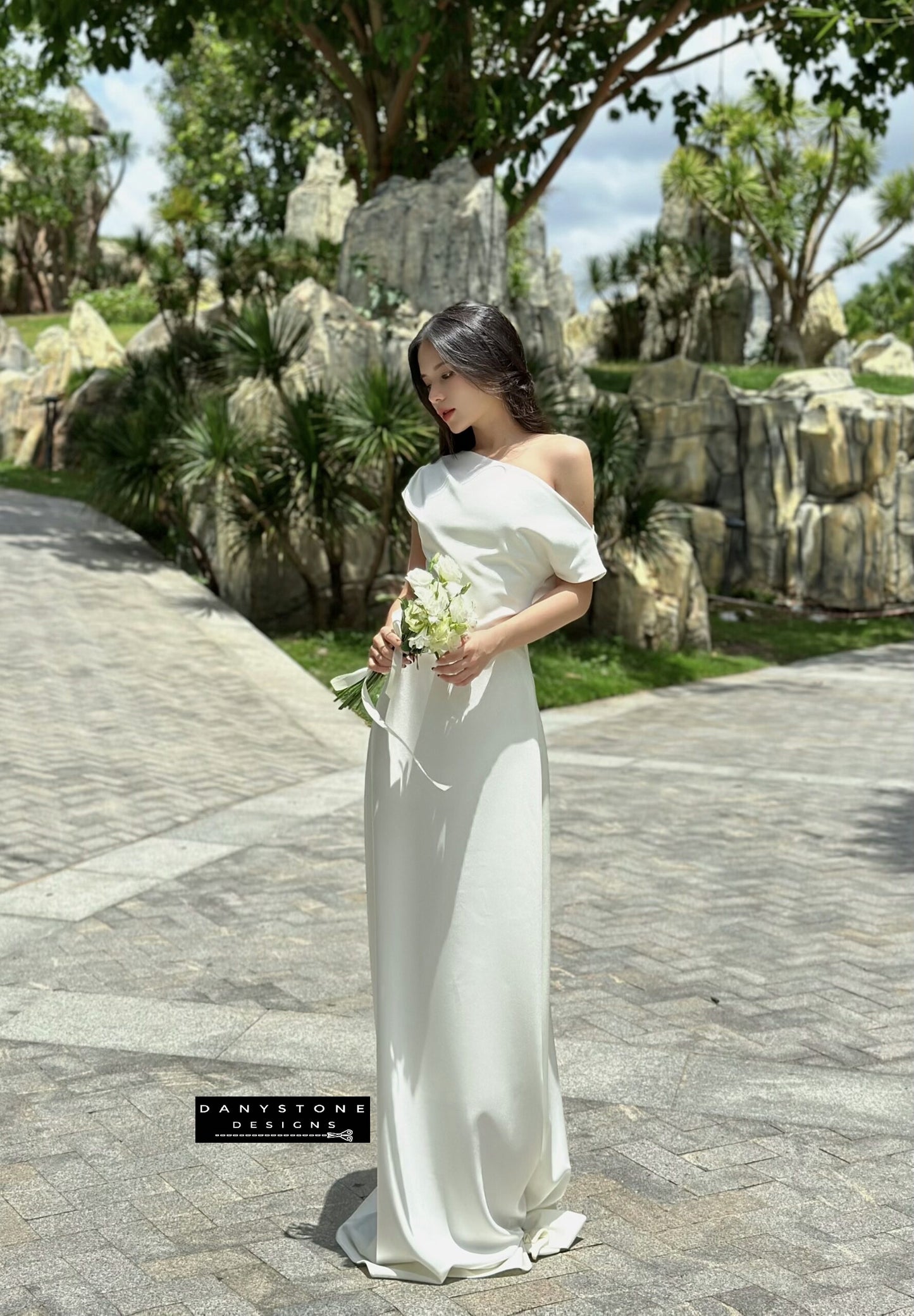 Model wearing an off-the-shoulder satin wedding dress, front view.