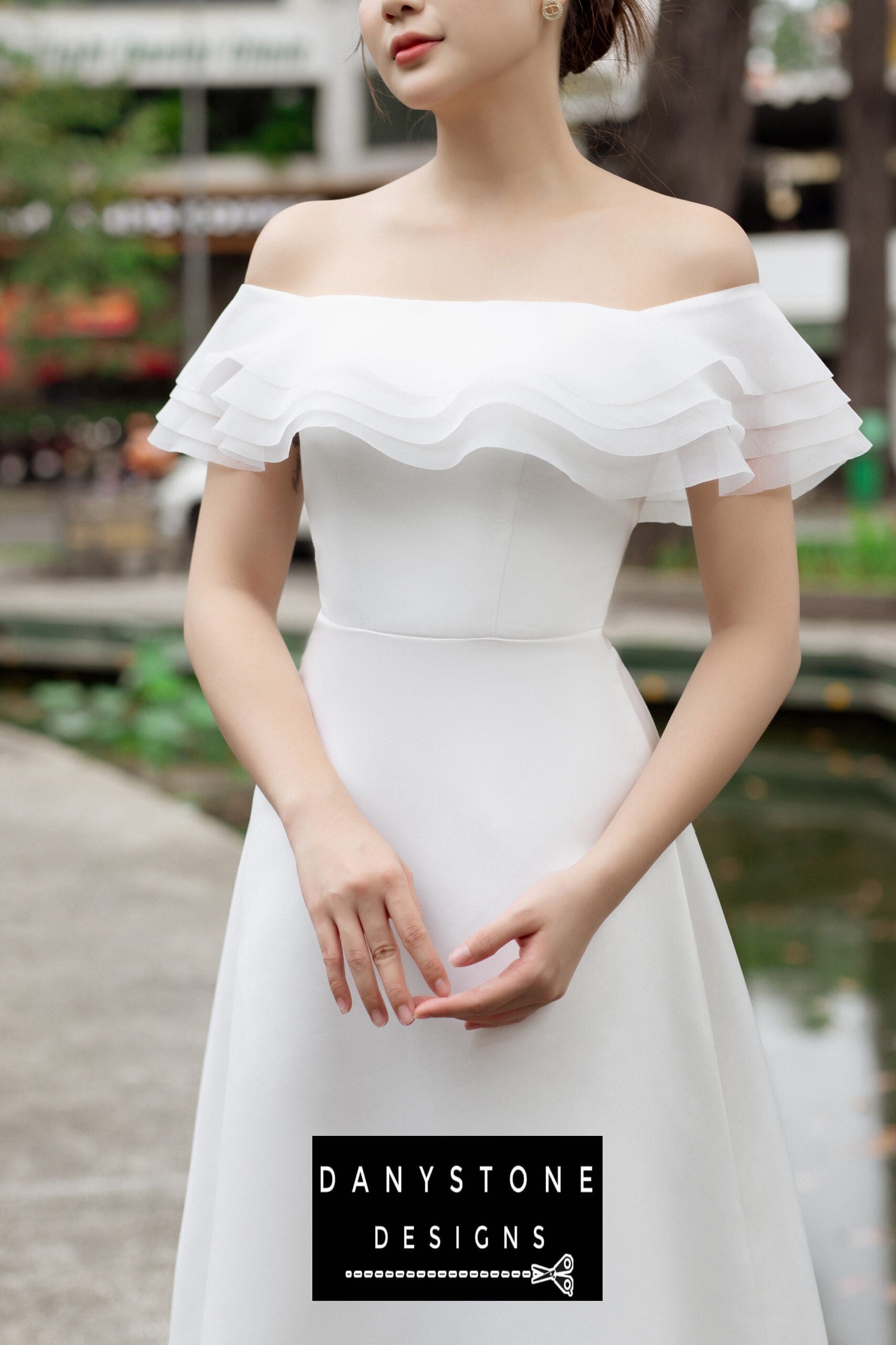 Close-up of the flat-shoulder design on a white midi dress, with layered ruffles adding texture.