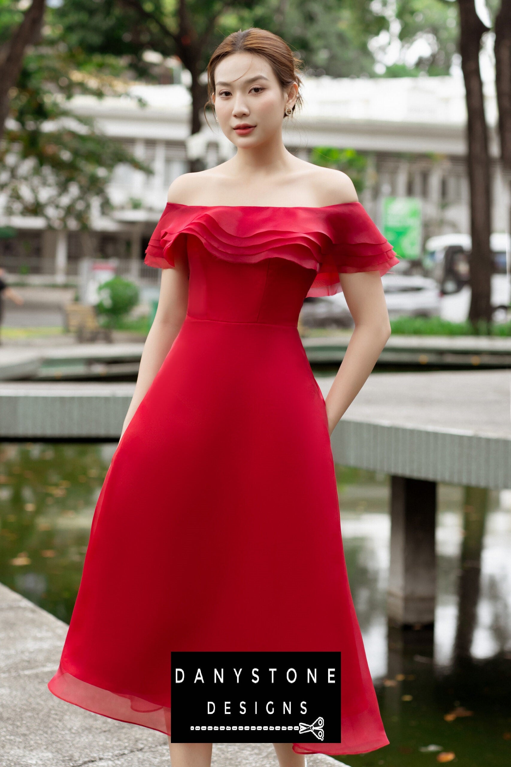 Model wearing an elegant red off-shoulder midi dress with layered ruffles