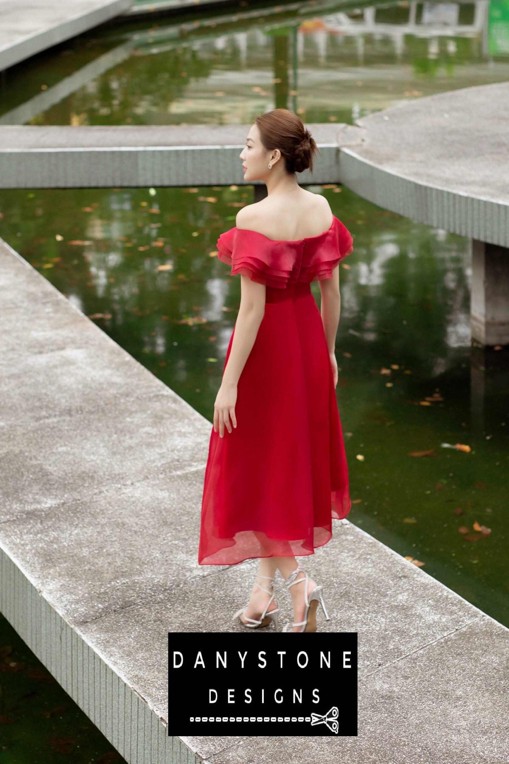 Red midi dress with off-shoulder design and layered ruffles modeled outdoors