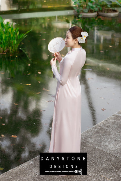 Back view of a woman wearing a pink silk chiffon Áo Dài, highlighting the elegant silhouette.