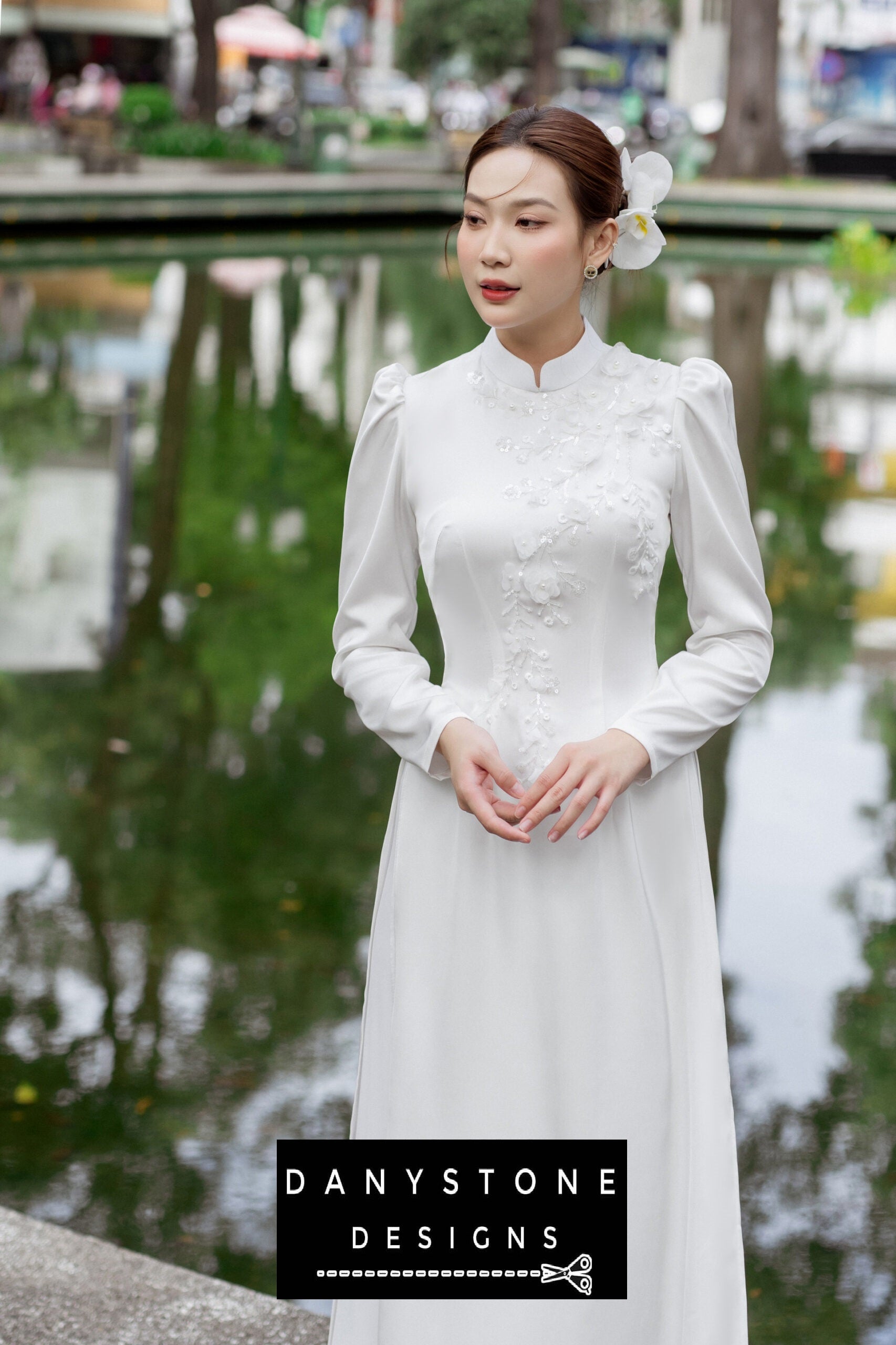 Woman in a white silk chiffon Áo Dài, highlighting the floral details and elegant design.