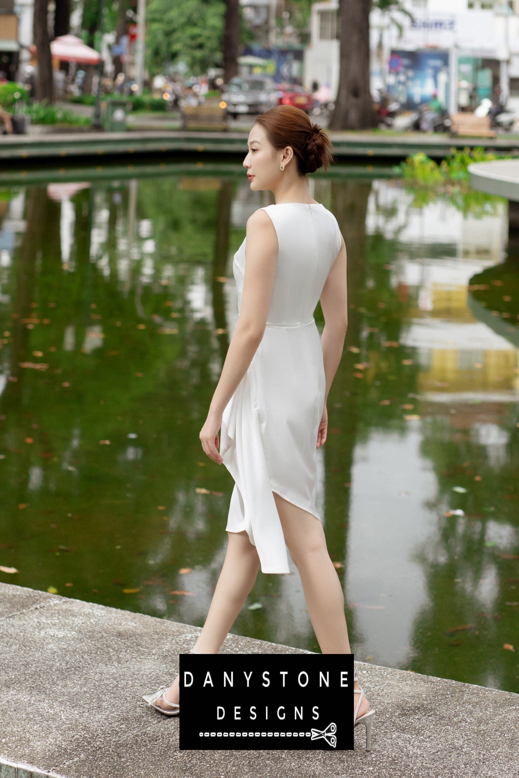 Back view of a woman in a short boat neck dress with pleated waist, showcasing the sleek silhouette.