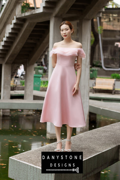 Pink midi dress with off-shoulder design and layered ruffles modeled outdoors