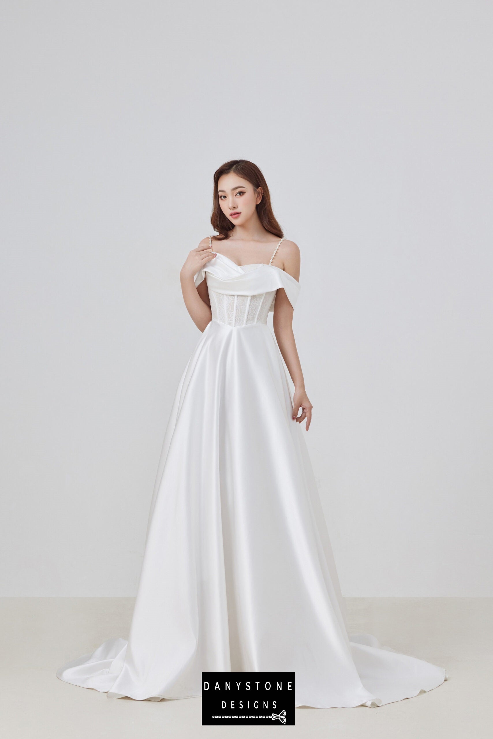 Make a stunning statement on your special day with this elegant satin corset lace off-shoulder wedding dress. The gown features delicate pearl straps and a beautifully structured bodice, exuding modern elegance and sophistication.