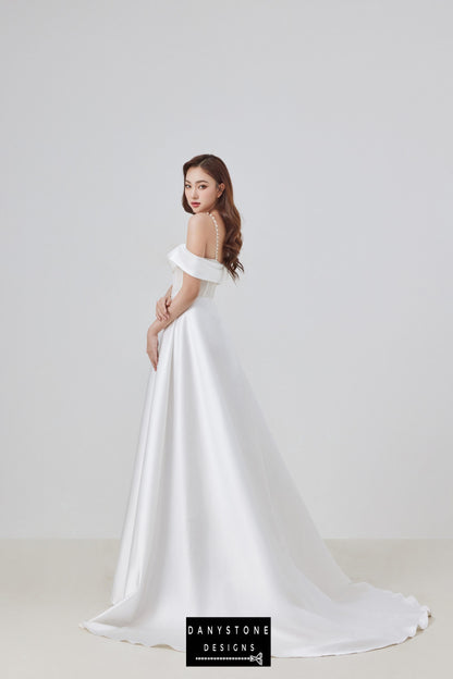 The back view of this elegant satin corset lace off-shoulder wedding dress highlights the delicate pearl straps and the graceful flow of the satin skirt, perfect for a sophisticated bridal look.