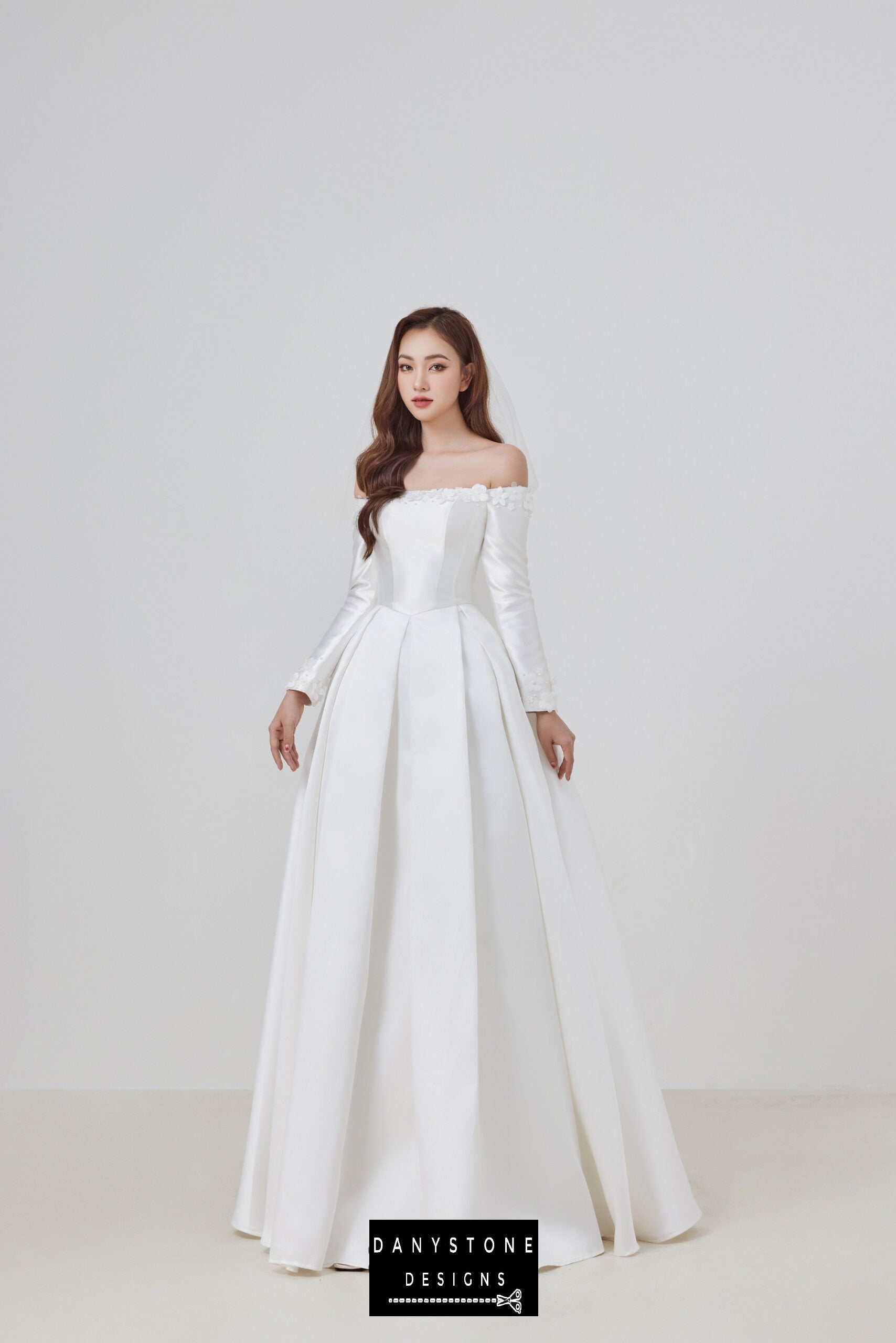 Make your wedding dreams come true with this stunning off-shoulder taffeta wedding dress. The elegant design features delicate 3D floral appliqués and a classic flat shoulder neckline, perfect for creating a romantic bridal look.