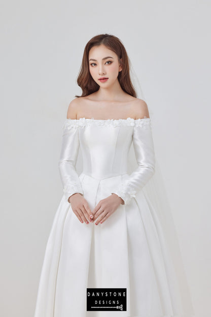 Featuring a classic flat shoulder neckline and exquisite 3D floral appliqués, this off-shoulder taffeta wedding dress is the perfect choice for the modern bride. The luxurious taffeta fabric offers a subtle sheen and structured silhouette.