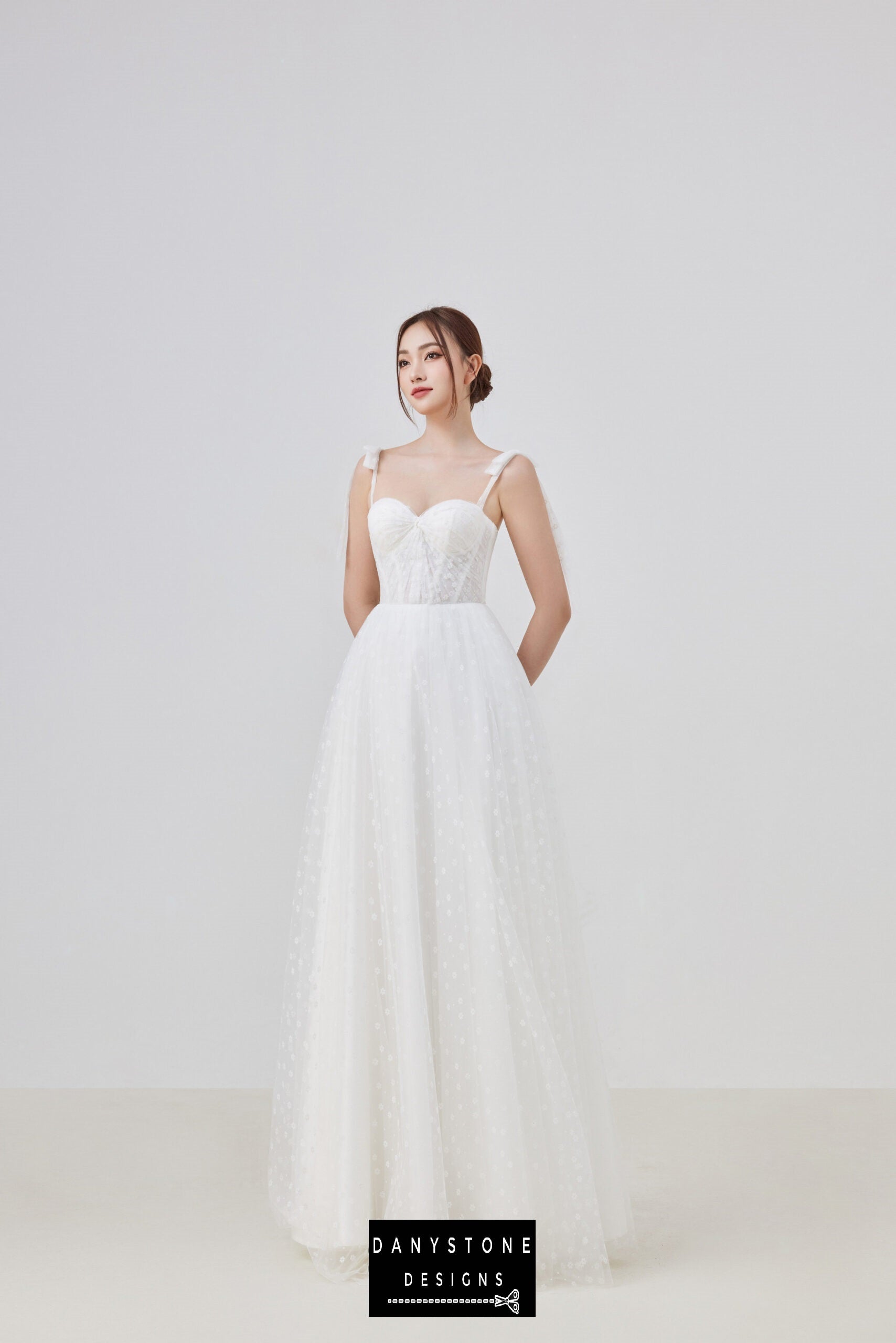 Front view of the elegant tulle corset wedding dress, highlighting the sweetheart neckline and delicate bow straps. The flowing tulle skirt creates a romantic silhouette perfect for the modern bride.