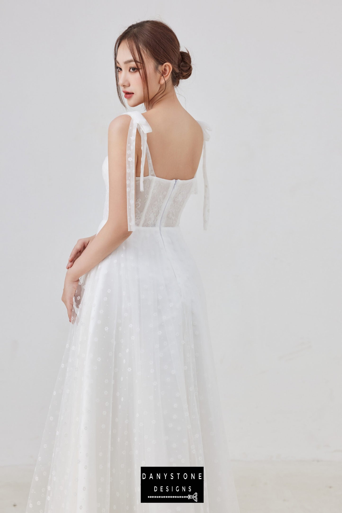 The back view of this elegant tulle corset wedding dress highlights the delicate bow straps and the light, airy feel of the flowing tulle skirt, perfect for a romantic bridal look.